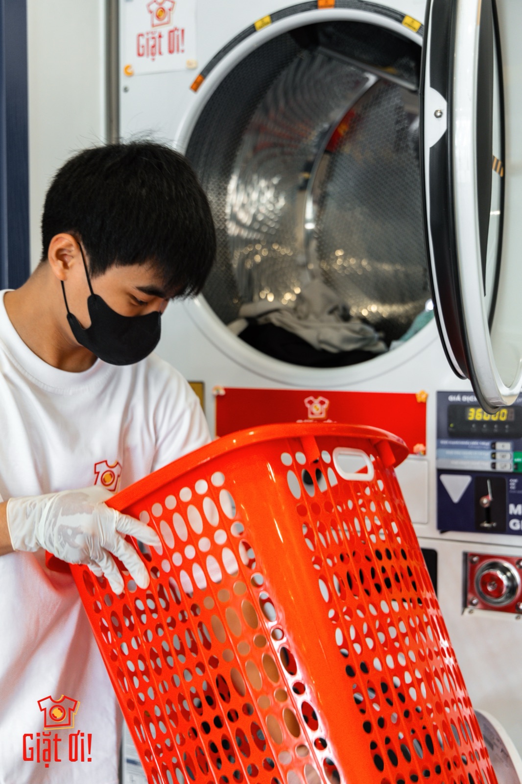 Nhân viên Giặt Ơi! đang phân loại đồ trong giỏ đỏ tại đối tác giặt — quy trình tách đồ trắng riêng để giặt